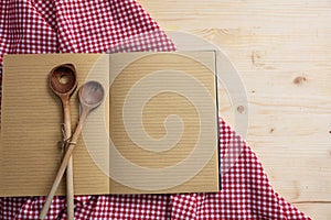 Notebook, kitchen utensils and red tablecloth on wooden table, top view, copy space