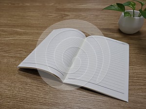 The notebook with lines  unfolded on a wooden table.