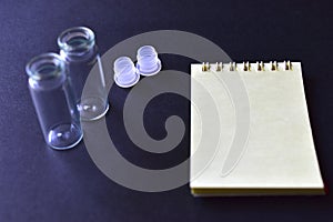 Notebook and medicine bottles on a black background