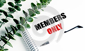 Notebook with members only text on white desk with pen and green leaves symbolizing exclusivity and restricted access