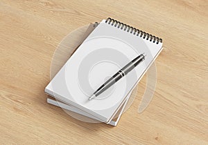 Notebook mockup. Two notebooks in a stack and pen. Spiral notepad on wooden background