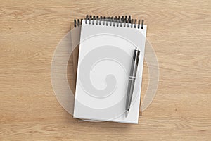 Notebook mockup. Two notebooks in a stack and pen. Spiral notepad on wooden background