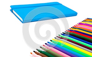 Notebook and multicolored markers on a white background