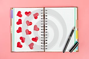 Notebook for note, pen and red hearts on a pink background