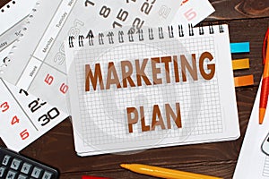 Notebook with a notes MARKETING PLAN on the office table with t