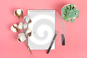 Notebook for notes, pen and sprig of cotton on a pink background