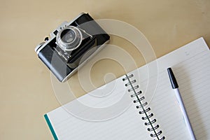 The Notebook And Old Vintage Folding Film Camera on The Wooden Table