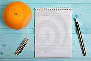 Notebook with orange fruit and pen