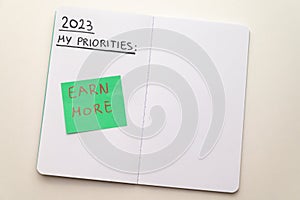 Notebook page, with text `2023 priorities: spend less, earn more` photo