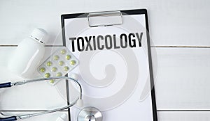 Notebook page with word - Toxicology nearby with a pills and pencil
