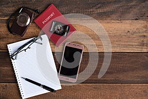 Notebook, passport, camera, compass and smarphone on a wooden table