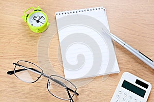 Notebook, pen, alarm clock on wooden desk