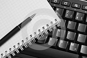 Notebook and pen on the black keyboard.