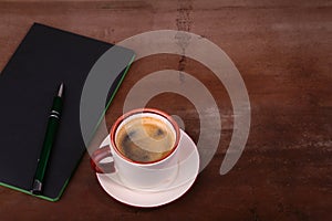 Notebook with pen and coffee cup on wooden background, business concept