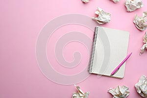 Notebook, pen and crumpled sheets of paper on light pink background, flat lay. Space for text