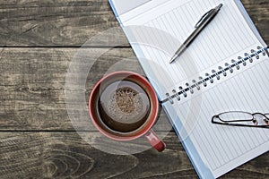 Notebook pen and cup of coffee on wood table