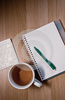 Notebook, pen and cup on wooden table