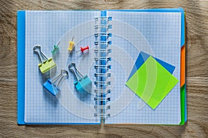 Notebook pen drawing pins paper clips on wooden board