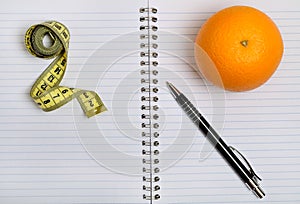 Notebook with pen and orange fruit