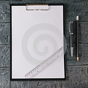 Notebook with pen, pencil and ruler on dark wooden table. The view from the top.