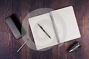 Notebook with pen on wooden table with a phone