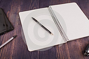 Notebook with pen on wooden table with a phone