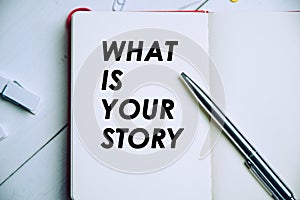 A notebook and pen with word `What is your Story`