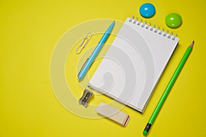 Notebook and pen on a yellow background. Top view with copy space. Stationery
