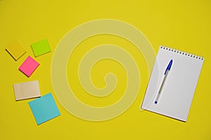 Notebook and pen on a yellow background. Top view with copy space. Stationery