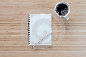 Notebook with pencil and coffee on old wooden table.Top view