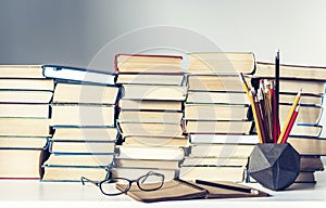 Notebook, pencils, glasses and stack of books, school background for education learning concept