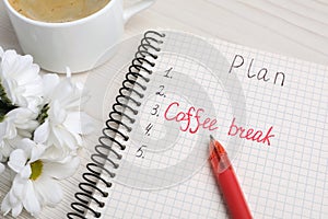 Notebook with phrase Coffee Break among plan items, cup of drink and flowers on white wooden table, closeup