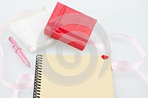 Notebook with pink pen and present boxes with ribbon decoration