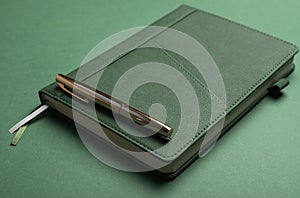 Notebook or planner with green cover over monochrome bsckground