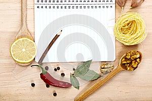 Notebook for recipes, vegetables and spices on wooden table