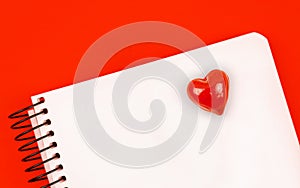 Notebook with red heart on it, love letter background concept with red table and copy space, top view photo