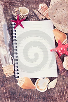 Notebook and seashells on wooden background