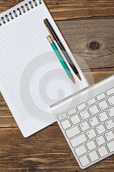 Notebook on a spring, vintage pencil, pen and computer keyboard