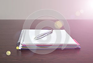 Notebook and steel pen on the table with sunlight