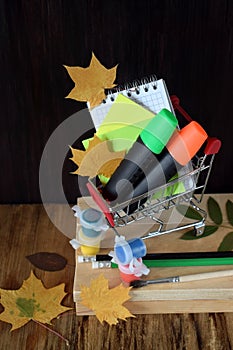 Notebook, stickers, highlighters in a shopping cart. Back to school shopping co