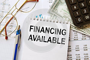 Notebook with text FINANCING AVAILABLE near office supplies