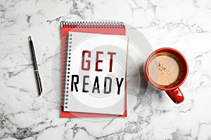 Notebook with text Get Ready, cup of coffee and pen on white marble, flat lay