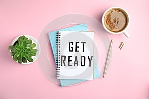 Notebook with text Get Ready, pen, cup of coffee and houseplant on pink background, flat lay