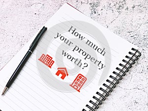 Notebook with text how much your property worth with a pen. Mortgage and real estate concept.