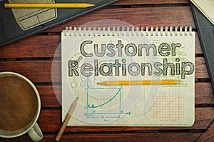 Notebook with text inside Customer Relationship on table with co