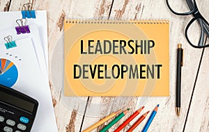 Notebook with text - Leadership Development, near office supplies