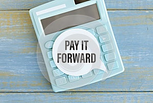 Text PAY IT FORWARD sheet of white paper for notes, calculator. Business concept