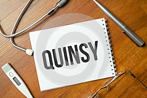 Notebook with text QUINSY with pen and stethoscope