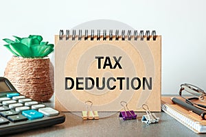 Notebook with text TAX DEDUCTION near office supplies