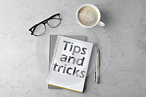 Notebook with text Tips and tricks on grey table, flat lay